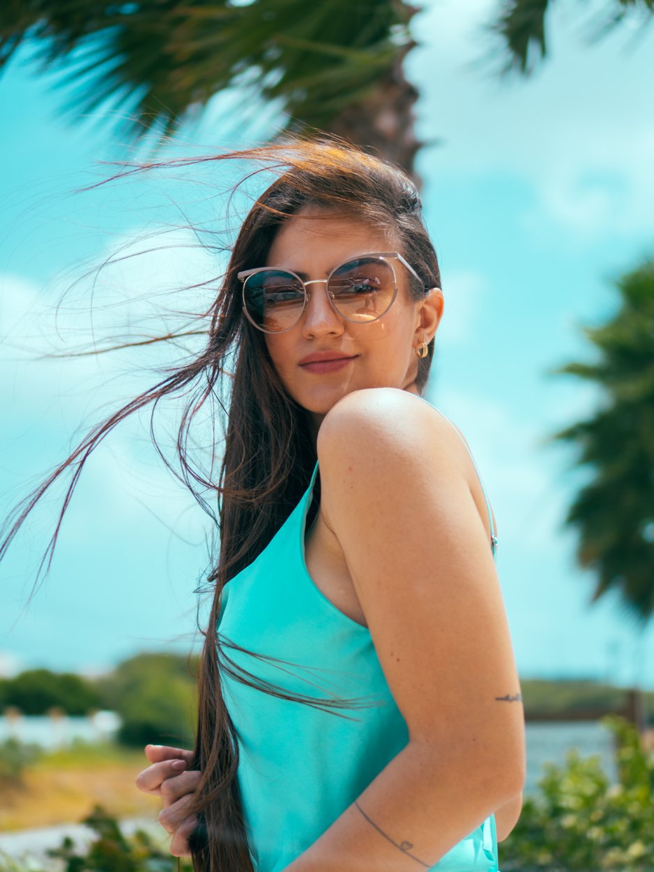 Woman wearing designer sunglasses outdoors under palm trees